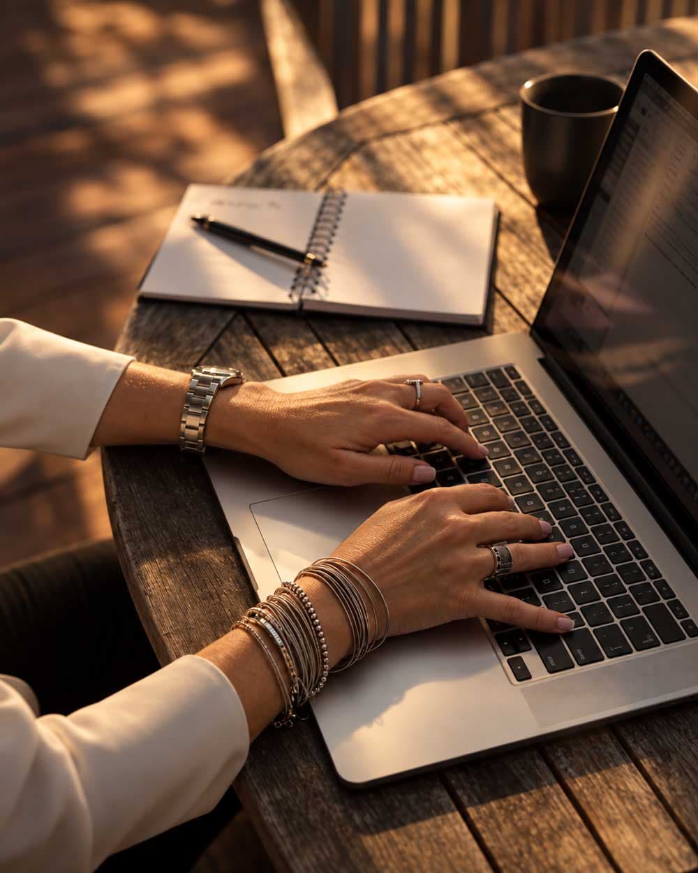 Mains d'une entrepreneure sur un ordinateur portable, un carnet à côté